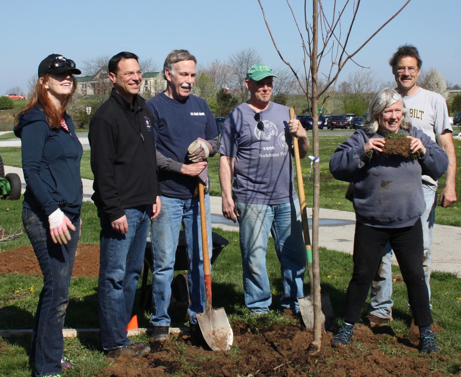 A planting crew standing with shovels beside a newly planted tree